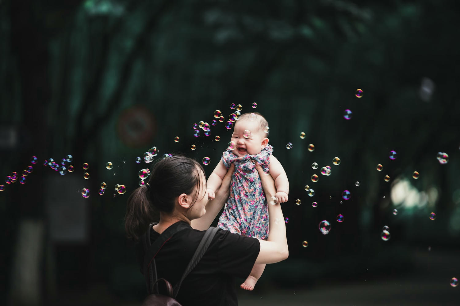 girl in black and pink dress blowing bubbles