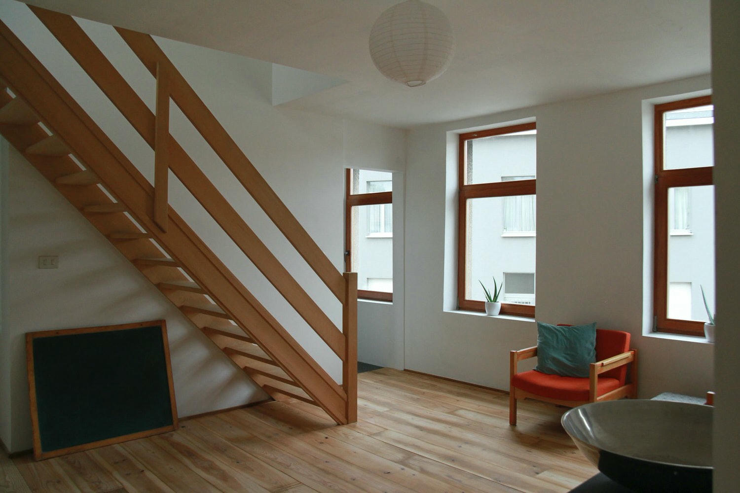 brown wooden framed red fabric padded armchair near stairs and window during daytime